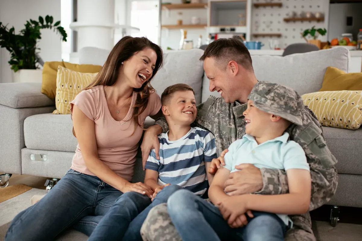 Happy soldier sitting on the floor of their living room with his wife and two kids.