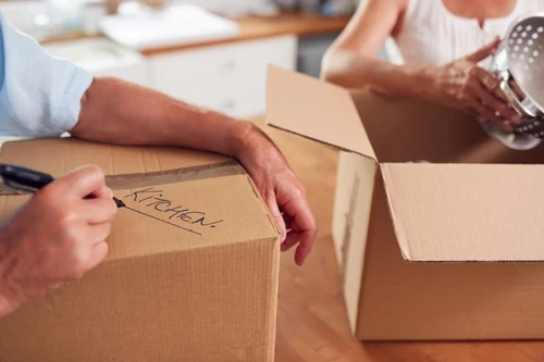 Man labeling a cardboard storage box "kitchen."