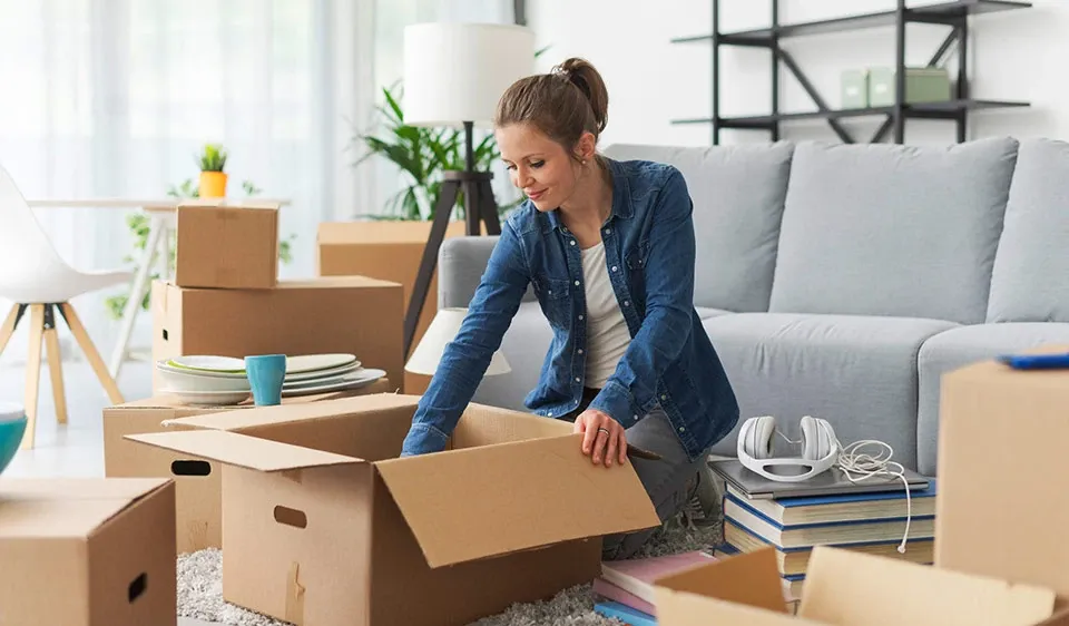 Woman unpacking household items in living room